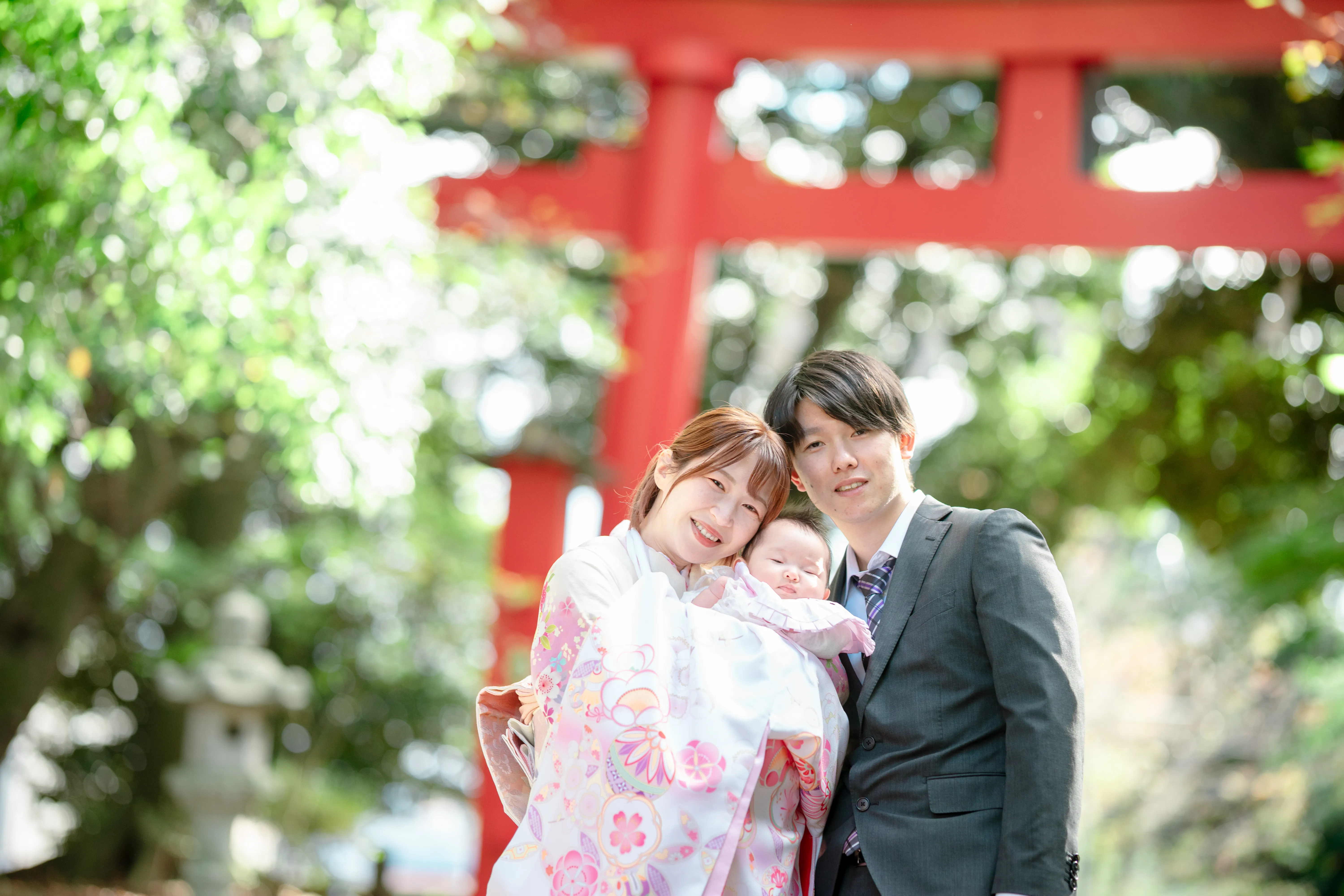 鳥居を背景にした産着の赤ちゃんとご家族