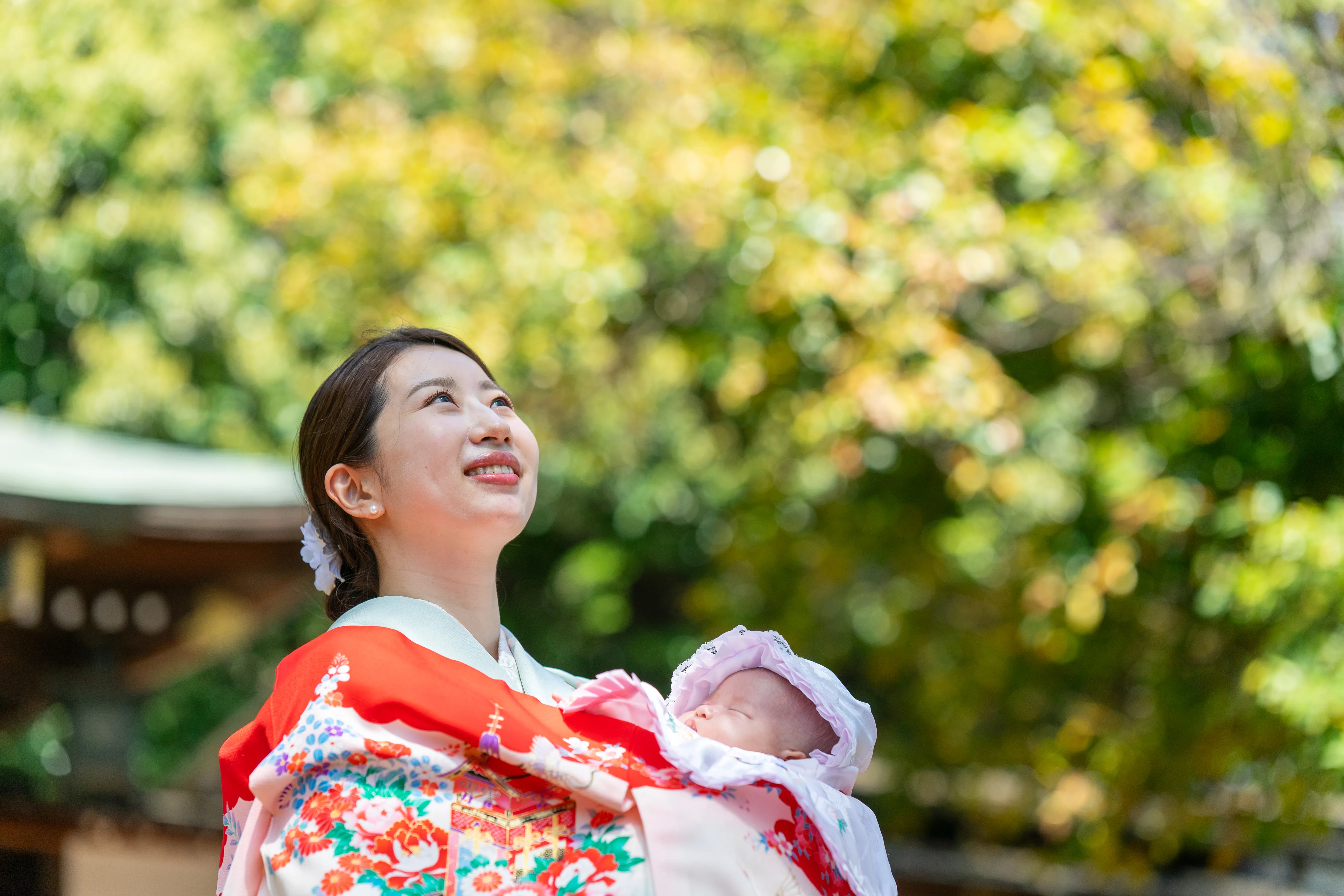 産着を着た赤ちゃんと見上げる母親